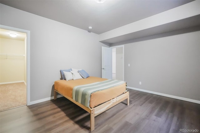 bedroom with a closet, a walk in closet, and dark hardwood / wood-style flooring