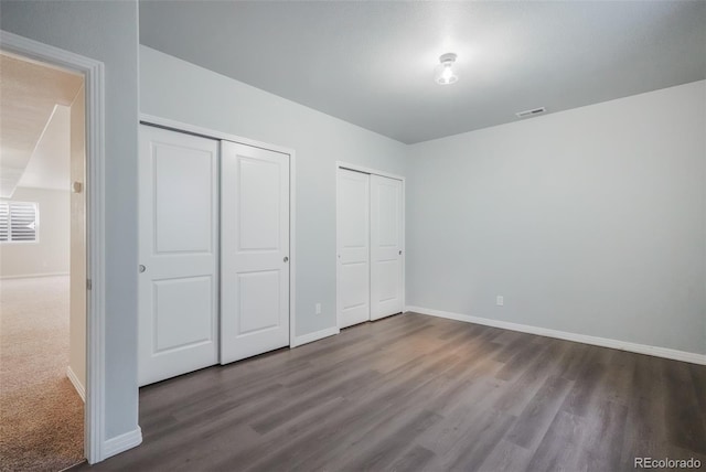 unfurnished bedroom with multiple closets and hardwood / wood-style floors