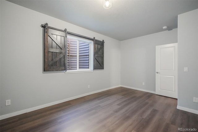 empty room with dark hardwood / wood-style flooring and a barn door