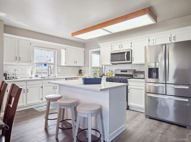 kitchen with white cabinetry, appliances with stainless steel finishes, a sink, and tasteful backsplash