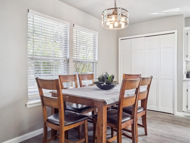dining area featuring baseboards, light wood finished floors, and a chandelier