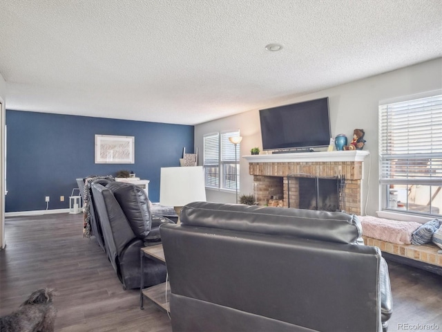living room featuring a brick fireplace, a textured ceiling, and wood finished floors