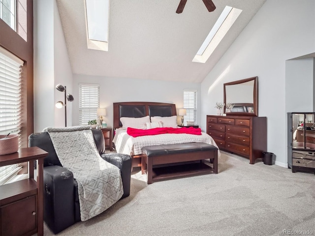 bedroom featuring carpet flooring, high vaulted ceiling, a skylight, and ceiling fan