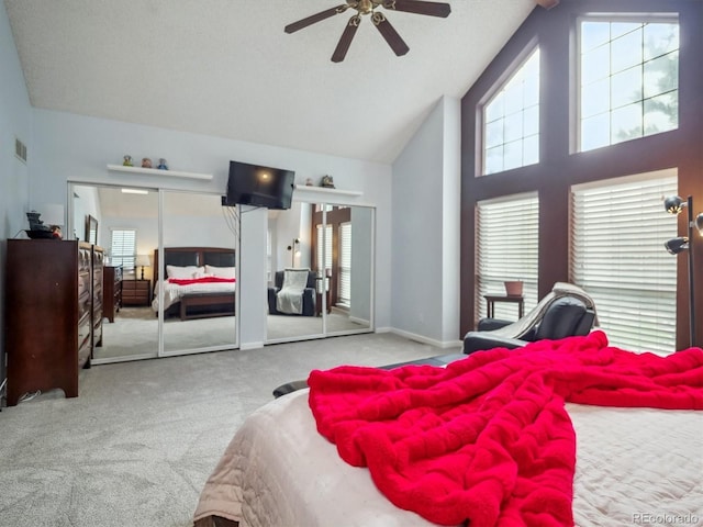 carpeted bedroom featuring ceiling fan, high vaulted ceiling, multiple closets, baseboards, and visible vents
