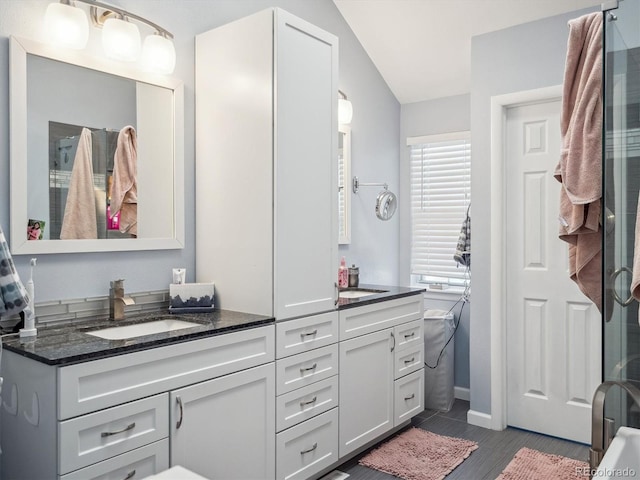 full bath featuring vanity, baseboards, and lofted ceiling