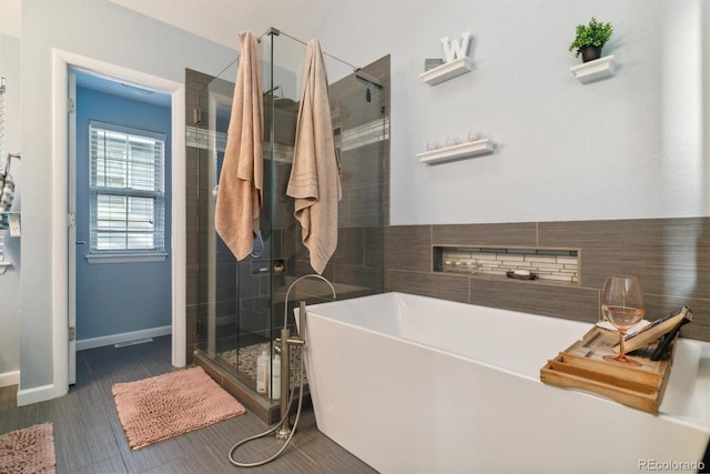 bathroom with baseboards, a stall shower, and a soaking tub