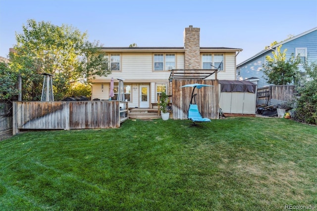 back of house featuring a lawn, a chimney, and a fenced backyard