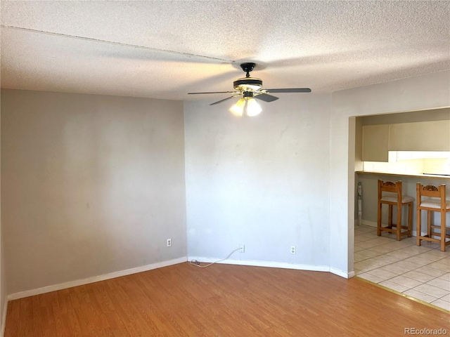 empty room featuring ceiling fan, light hardwood / wood-style floors, and a textured ceiling