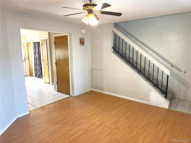 unfurnished living room featuring ceiling fan, light hardwood / wood-style floors, and a textured ceiling