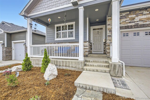 doorway to property featuring a porch, stone siding, and an attached garage