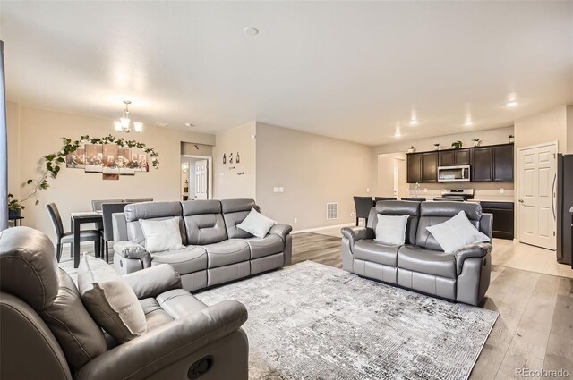 living area with a chandelier, light wood-style floors, and baseboards