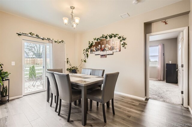 dining room featuring a chandelier, light wood finished floors, and baseboards