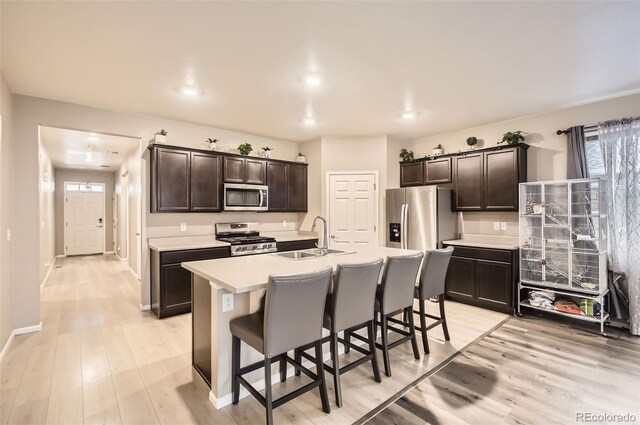 kitchen with stainless steel appliances, a sink, a breakfast bar, and dark brown cabinets