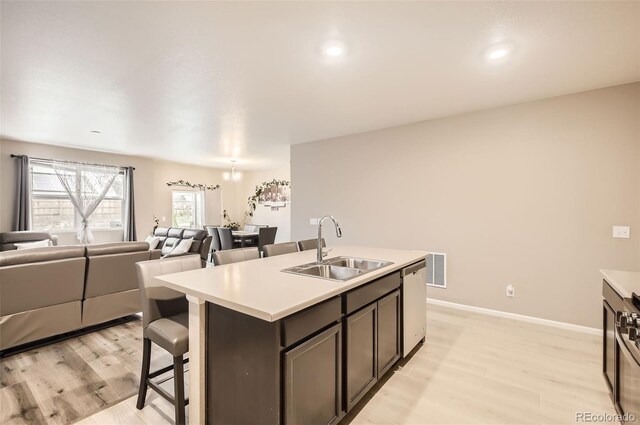 kitchen with a sink, stainless steel dishwasher, light wood-style floors, open floor plan, and recessed lighting