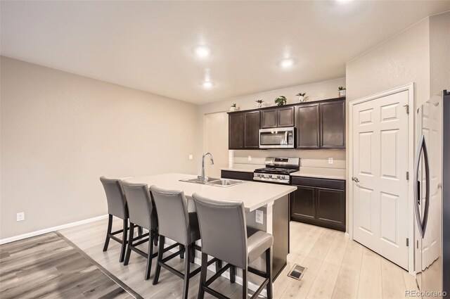 kitchen featuring appliances with stainless steel finishes, a breakfast bar, a sink, and an island with sink