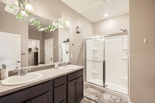 full bathroom featuring a stall shower, double vanity, and a walk in closet