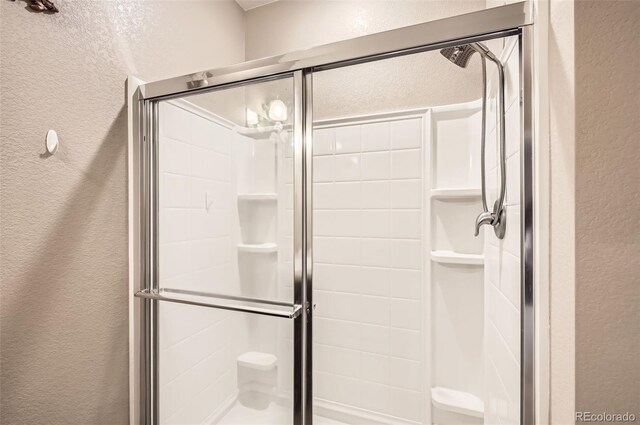 full bath featuring a textured wall and a stall shower