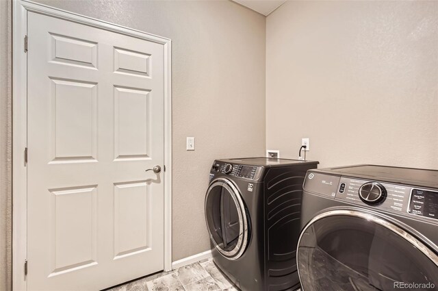 clothes washing area with independent washer and dryer and baseboards