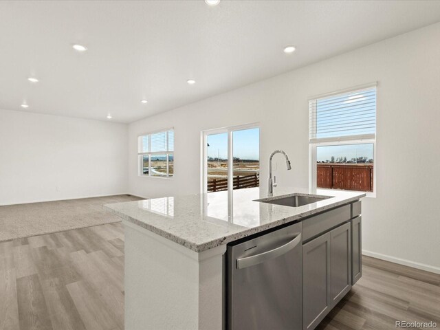 kitchen featuring light stone countertops, recessed lighting, a sink, light wood-style floors, and dishwasher