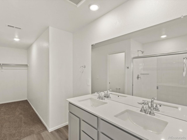 bathroom featuring a sink, visible vents, double vanity, and a shower stall