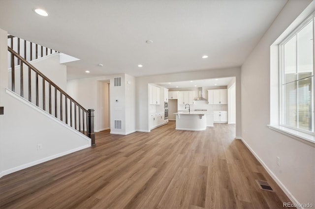 unfurnished living room featuring sink and light hardwood / wood-style flooring