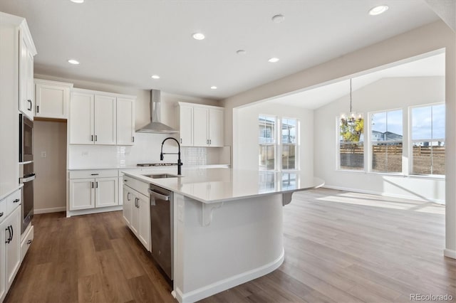 kitchen featuring wood-type flooring, a kitchen island with sink, white cabinets, wall chimney range hood, and vaulted ceiling