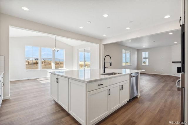 kitchen featuring a wealth of natural light, vaulted ceiling, and an island with sink