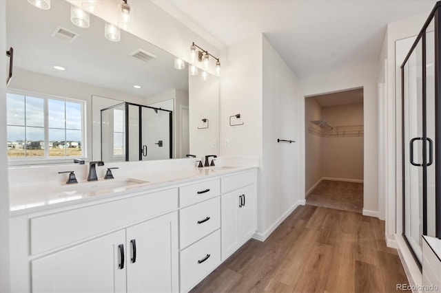 bathroom with hardwood / wood-style flooring, vanity, and walk in shower