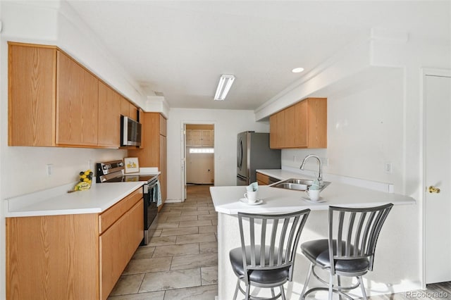 kitchen featuring a breakfast bar area, a peninsula, a sink, stainless steel appliances, and light countertops