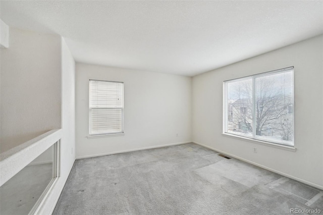 carpeted spare room with baseboards and visible vents