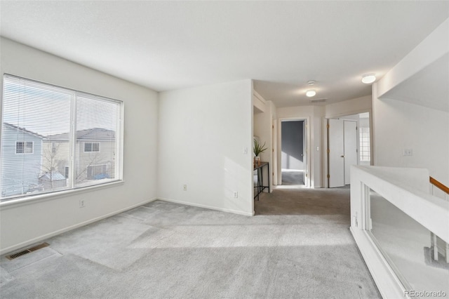 carpeted spare room with visible vents and baseboards