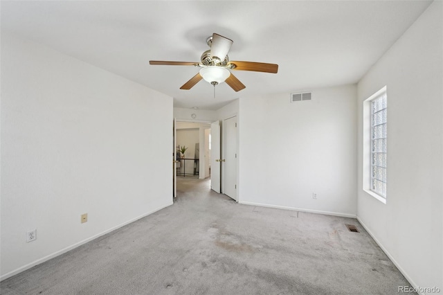 empty room with a wealth of natural light, visible vents, and carpet flooring