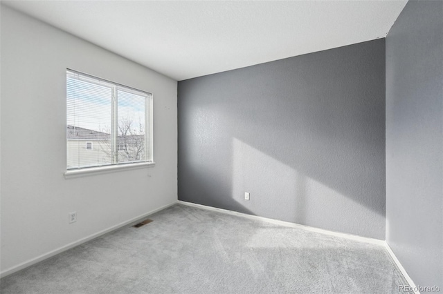 carpeted empty room featuring visible vents and baseboards