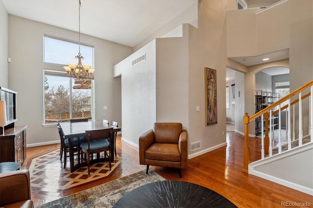 10358 Kelliwood Way, Highlands Ranch, CO 80126 - dining room featuring a towering ceiling, a chandelier, baseboards, wood finished floors, and stairs