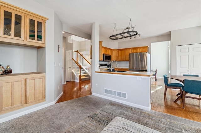 10358 Kelliwood Way, Highlands Ranch, CO 80126 - kitchen featuring stainless steel appliances, light colored carpet, glass insert cabinets, baseboards, and a peninsula