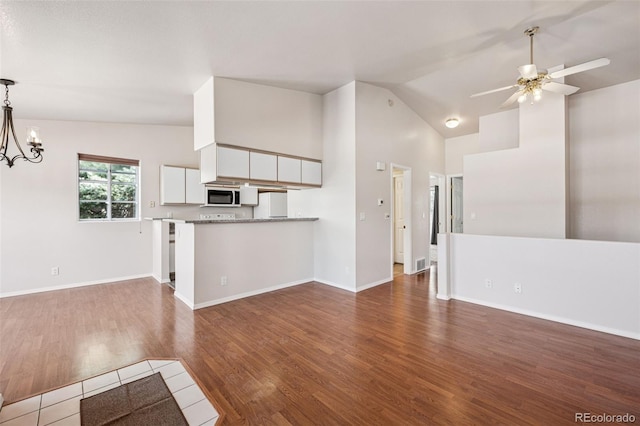 6087 Colony Cir, Colorado Springs, CO 80919 - unfurnished living room featuring a ceiling fan, dark wood-style flooring, a chandelier, baseboards, and high vaulted ceiling