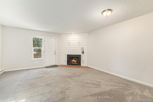 unfurnished living room featuring a textured ceiling, carpet flooring, and a large fireplace