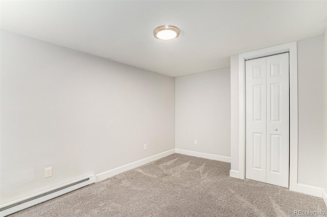 unfurnished bedroom featuring a baseboard heating unit, carpet, and a closet