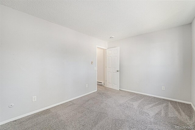 spare room featuring a baseboard radiator, carpet floors, and a textured ceiling