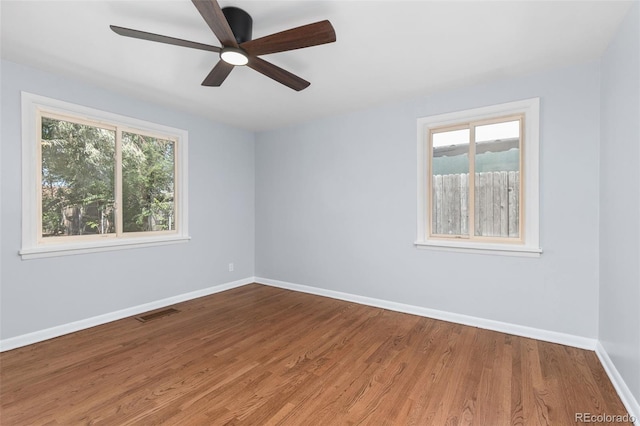 spare room featuring wood-type flooring, a healthy amount of sunlight, and ceiling fan