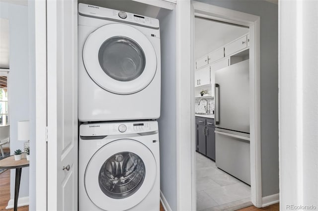 washroom with stacked washer and dryer, sink, and light tile patterned floors