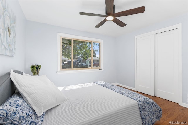 bedroom with dark hardwood / wood-style flooring, ceiling fan, and a closet