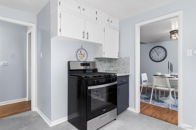 kitchen featuring light tile patterned floors, decorative backsplash, stainless steel gas range oven, and white cabinets