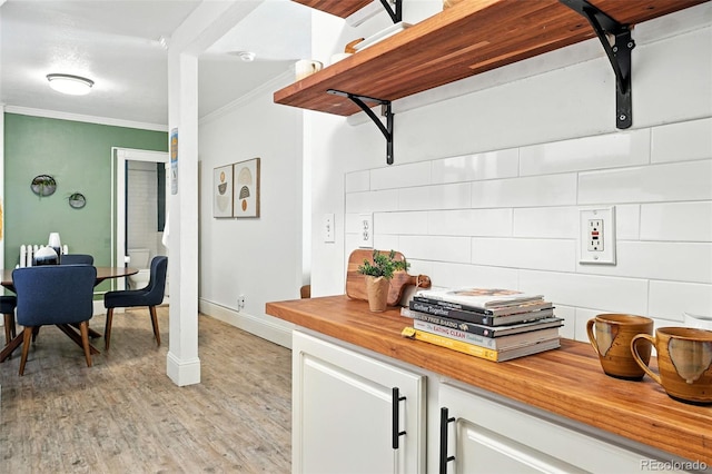 1137 N Sherman St Unit 17, Denver, CO 80203 - kitchen featuring crown molding, white cabinetry, light wood finished floors, decorative backsplash, and butcher block countertops