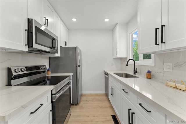 10687 W 107th Ave, Broomfield, CO 80021 - kitchen featuring appliances with stainless steel finishes, white cabinetry, light wood finished floors, recessed lighting, and light stone countertops