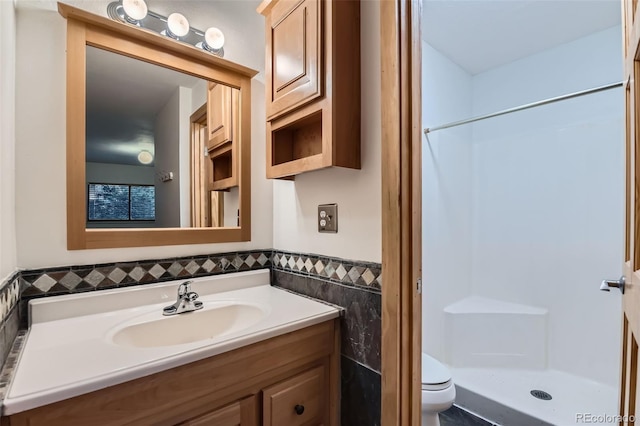 695 Manhattan Dr Unit 109, Boulder, CO 80303 - bathroom featuring a shower stall, toilet, vanity, tile walls, and wainscoting