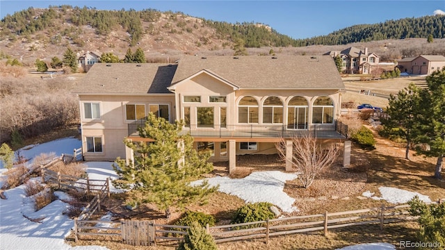 snow covered back of property featuring a mountain view and a balcony