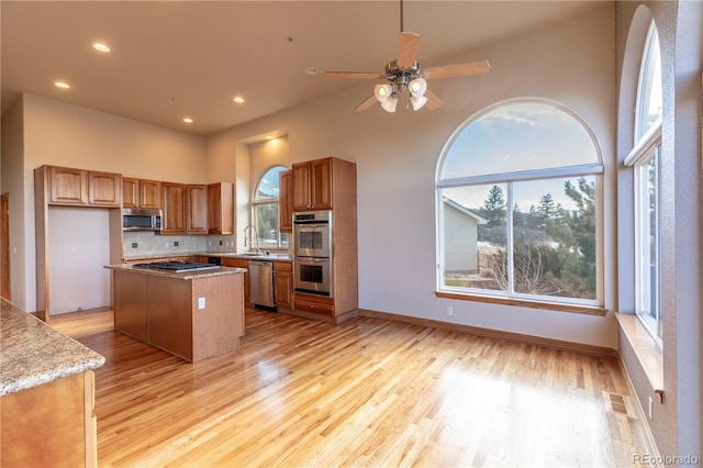 kitchen featuring a center island, appliances with stainless steel finishes, backsplash, and light wood-type flooring