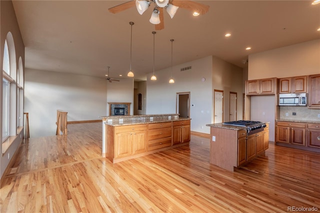 kitchen featuring appliances with stainless steel finishes, a center island, light wood-type flooring, and tasteful backsplash