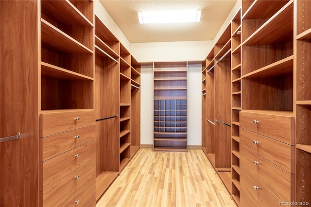 walk in closet with light hardwood / wood-style floors